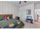 A bedroom with paneled accent wall, ceiling fan, and open doorway to living area at 5018 Towneship Creek Rd, Roswell, GA 30075