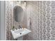 Chic powder room featuring patterned wallpaper, a pedestal sink, and elegant gold fixtures at 5018 Towneship Creek Rd, Roswell, GA 30075