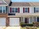 Townhouse featuring a garage, brick facade and a red door with white pillars at 7229 Georges Way, Morrow, GA 30260
