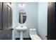 Powder room featuring pale blue walls, pedestal sink, and a decorative oval mirror at 115 Oak Grove Pl, Acworth, GA 30102