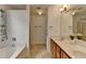Bathroom features a tub with shower, tiled floor, double sink with wooden cabinets, and a large mirror at 3517 Harvest Ridge Ln, Buford, GA 30519
