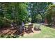 Backyard fire pit with Adirondack chairs offers a relaxing outdoor space surrounded by lush greenery and natural light at 2005 Westbourne Way, Alpharetta, GA 30022