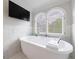 Bright bathroom featuring a freestanding tub, plantation shutters, stylish fixtures, and marble tile at 2005 Westbourne Way, Alpharetta, GA 30022