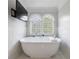 Elegant white bathtub with marble tile surround, offering a serene spa-like retreat with window views at 2005 Westbourne Way, Alpharetta, GA 30022