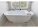 Elegant white bathtub with marble tile surround, offering a serene spa-like retreat with window views at 2005 Westbourne Way, Alpharetta, GA 30022