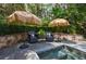Backyard jacuzzi tub featuring stone patio, tropical umbrellas, and lush landscaping at 2005 Westbourne Way, Alpharetta, GA 30022