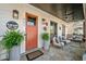 Stylish front porch with an orange door, potted ferns, stone flooring, and comfortable seating for relaxation and outdoor living at 561 S Club Dr, Woodstock, GA 30188