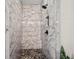 Luxurious marble-tiled shower with pebble-stone flooring and built-in bench at 561 S Club Dr, Woodstock, GA 30188