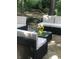 Outdoor patio area with stylish black wicker furniture, glass table, and lush green landscaping at 1201 Lake Washington Dr, Lawrenceville, GA 30043