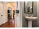 Hallway with hardwood floors leading to living room and powder room with pedestal sink at 817 Nevis Way, Mcdonough, GA 30253