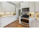 Bright kitchen features granite counters, white cabinets, and stainless steel appliances at 5489 White Cedar Ter, Sugar Hill, GA 30518