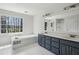 Bathroom featuring a large tub under a window, a dual-sink vanity, and white tile floors at 6317 Southland Forest Dr, Stone Mountain, GA 30087