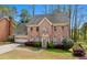 Two-story brick home with attached garage surrounded by mature trees and landscaped front yard at 6317 Southland Forest Dr, Stone Mountain, GA 30087