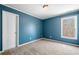 Bedroom with blue walls, carpet, a window overlooking a wooded area, and door at 100 Oakwind Pkwy, Canton, GA 30114
