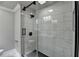 Bathroom featuring a glass enclosed shower with a black fixture and white marble tiles and dark herringbone floor at 5155 Rosestone Nw Dr, Lilburn, GA 30047