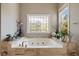 Bathroom featuring a jetted soaking tub with tile surround and decorative window at 3720 River Mansion Dr, Peachtree Corners, GA 30096