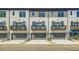 Townhome exterior with balconies over garages, gray doors, white brick, and gray siding at 608 Marimba Pike, Mcdonough, GA 30253