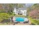 A backyard view of a bright blue swimming pool, patio furniture, and a lovely white house with a well maintained backyard at 1260 Centenary Rdg, Snellville, GA 30078