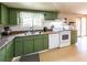 Well-lit kitchen featuring white appliances, green cabinetry, and ample counter space at 6348 Garnet Dr, Douglasville, GA 30135