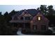 Elegant two-story brick home adorned with festive blue and yellow lights at dusk with a welcoming porch at 5265 Cole Creek Ln, Cumming, GA 30040