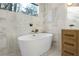 Modern bathroom featuring a standalone tub, marble walls, and pebble tile flooring at 3306 Sleepy Se Ln, Smyrna, GA 30080