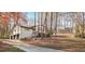 Charming home exterior featuring a two-car garage, long driveway, and mature trees in a wooded setting at 3306 Sleepy Se Ln, Smyrna, GA 30080