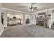Open concept living room featuring a stone fireplace, neutral carpeting, and seamless flow into the kitchen at 4315 Balsam Bark Dr, Cumming, GA 30028