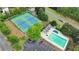 Overhead view of tennis courts next to pool and parking lot with mature trees in a well-maintained community at 7040 Shady Oak Ln, Cumming, GA 30040
