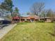 Charming brick home featuring a well-manicured lawn, mature trees, and red awnings at 1368 Scott Blvd, Decatur, GA 30030