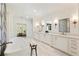 Bright bathroom featuring stone floors, double vanity, designer mirrors and a soaking tub at 312 Meadow Dr, Alpharetta, GA 30009
