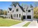 Elegant white brick home with black trim, a well-manicured lawn, and a spacious driveway leading to attached garages at 312 Meadow Dr, Alpharetta, GA 30009