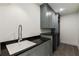 Well-organized laundry room with gray cabinets, black countertop, sink, and tile flooring at 312 Meadow Dr, Alpharetta, GA 30009