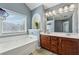 Bathroom featuring a soaking tub, double sink vanity with wood cabinets and a window at 6015 Crestwick Way, Cumming, GA 30040