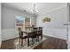 Dining room with dark wood table and chairs, hardwood floors, wainscoting and modern chandelier at 6015 Crestwick Way, Cumming, GA 30040