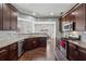 Modern kitchen with stainless steel appliances, granite countertops, dark wood cabinets, and white subway tile backsplash at 6015 Crestwick Way, Cumming, GA 30040