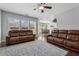 Open-concept living room with hardwood floors, leather sofas, ceiling fan and large windows overlooking the backyard at 6015 Crestwick Way, Cumming, GA 30040