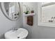Charming powder room with a round silver mirror, neutral colored walls, modern fixtures and a cute shelf at 6015 Crestwick Way, Cumming, GA 30040
