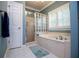 Bright bathroom showcasing a soaking tub with marble surround, a glass block window, and a separate glass enclosed shower at 1187 Plantation Dr, Villa Rica, GA 30180