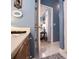 Bathroom leading into a bedroom with a glimpse of the bed and bedside table, featuring blue walls and neutral tile at 1187 Plantation Dr, Villa Rica, GA 30180