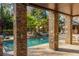 Covered outdoor patio with stone columns overlooking a sparkling pool and lush landscaping at 2461 Oak Grove Ne Ests, Atlanta, GA 30345