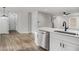 Open kitchen featuring white cabinetry, stainless steel appliances, hardwood floors, and an island with a sink at 6355 Akins Way, Cumming, GA 30041