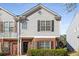 Close-up of a brick and grey sided townhome featuring a black front door and manicured bushes at 4917 Walden Lake Sq, Decatur, GA 30035