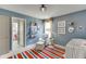Bedroom featuring a chair, ottoman, rug, shelves, and a decorated crib, providing a cozy space at 1788 Hanover West Ct, Lawrenceville, GA 30043
