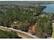 Aerial view showcasing the property under construction nestled among dense trees and proximity to a lake at 3240 Miller Bottom Rd, Conyers, GA 30012