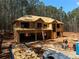 Two-story home under construction with a wooded lot, showcasing the framing and initial roof work at 3240 Miller Bottom Rd, Conyers, GA 30012