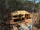 Two-story home under construction with a wooded lot, showcasing the framing and initial roof work at 3240 Miller Bottom Rd, Conyers, GA 30012