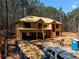 Two-story home under construction with a wooded lot, showcasing the framing and initial roof work at 3240 Miller Bottom Rd, Conyers, GA 30012