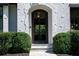 Elegant arched front door with black frame and textured white brick facade at 5495 Mount Vernon Pkwy, Atlanta, GA 30327