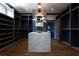 Spacious walk-in closet with dark shelving, hardwood floors, marble island, and decorative chandelier at 5495 Mount Vernon Pkwy, Atlanta, GA 30327