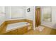 Bathroom featuring a soaking tub with tiled surround, shower with curtains, and neutral tile floors at 302 Cimarron Way, Lawrenceville, GA 30044